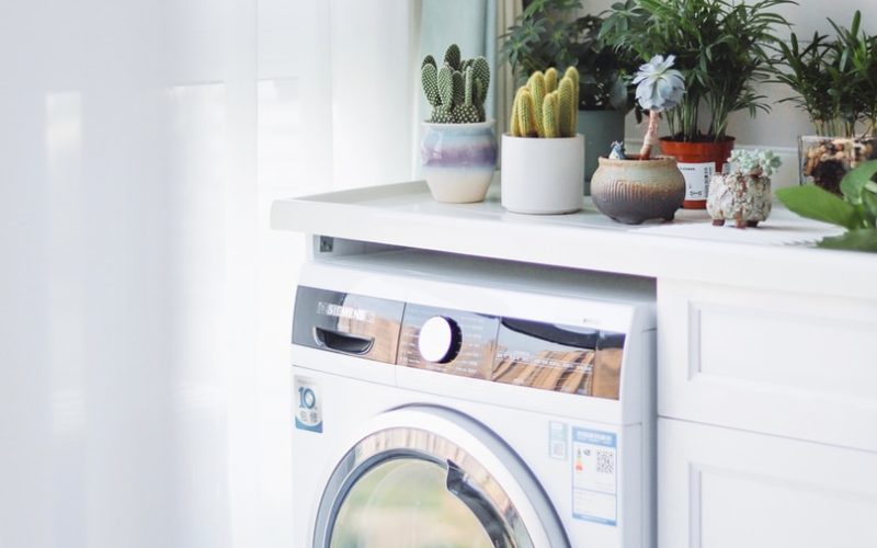 white front load washing machine beside white wooden cabinet
