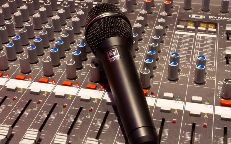 black wireless microphone on grey and multicolored audio mixer
