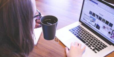 woman holding tea filled mug using MacBook